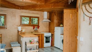 A compact kitchen with wooden walls, a white stove, and a washing machine. - Cabane "les 3 Complices" (Labastide de Virac)