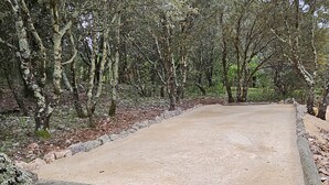 A paved area surrounded by trees and a stone wall. - Cabane "les 3 Complices" (Labastide de Virac)