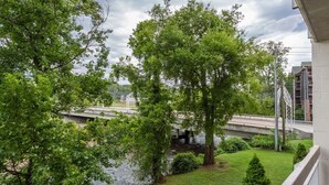 A view of a river with a bridge, lush green trees, and a grassy area. - Riverfront Condo Pigeon Forge (Pigeon Forge)
