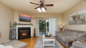 A living room with a fireplace, a sofa, a coffee table, and a ceiling fan. - Riverfront Condo Pigeon Forge (Pigeon Forge)