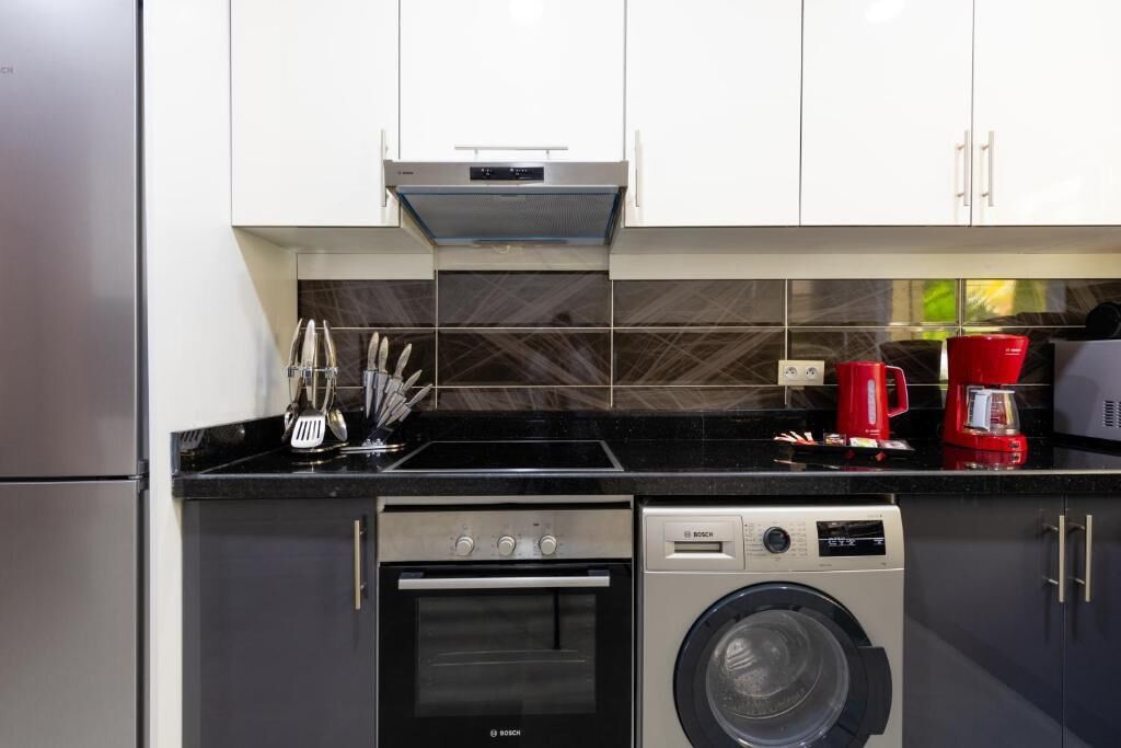 Una cocina compacta con horno Bosch, lavadora y cafetera.
