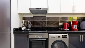 Una cocina compacta con horno Bosch, lavadora y cafetera.