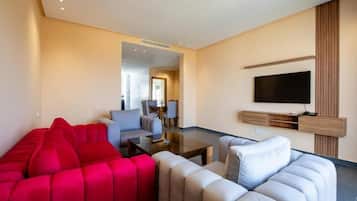 A modern living room with a red sofa, a grey sofa, a coffee table, and a flat-screen TV mounted on the wall.