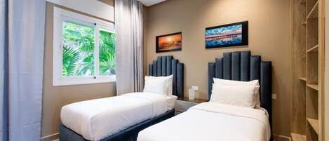 A hotel room with two beds, a large window with a view of palm trees, and artwork on the walls.