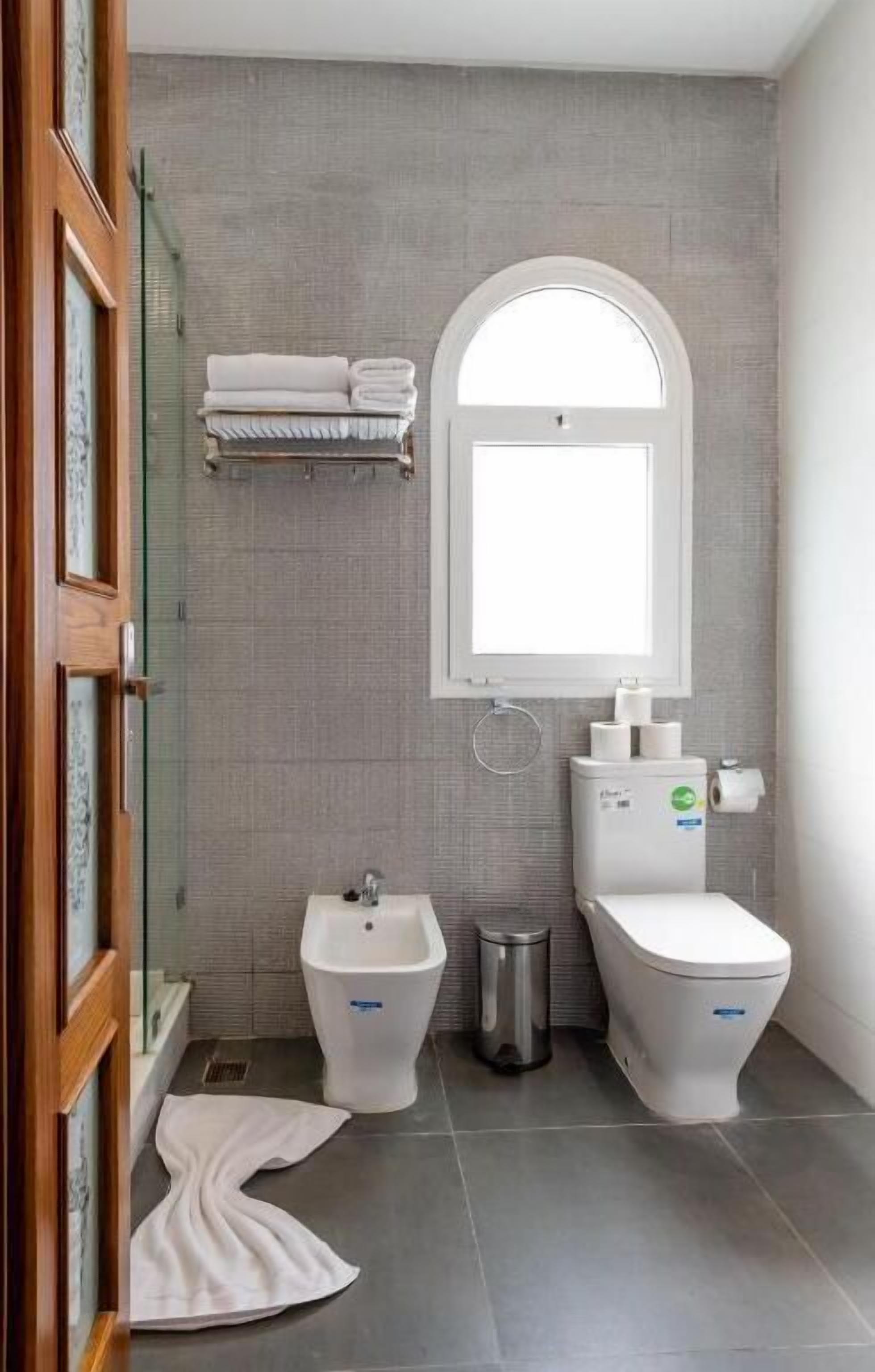 Een moderne badkamer met een toilet, handdoekrek en een bidet.