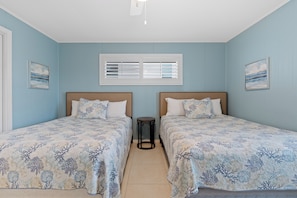 Een slaapkamer met twee bedden, een raam met zonwering en kunstwerken aan de wanden.