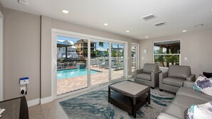 Un salon spacieux avec vue sur la piscine, comprenant un canapé, une table basse et une cheminée.