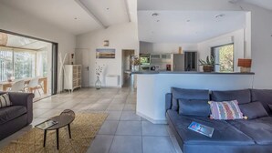 A modern living space with a grey sofa, a small coffee table, and a dining area with chairs and a table.
