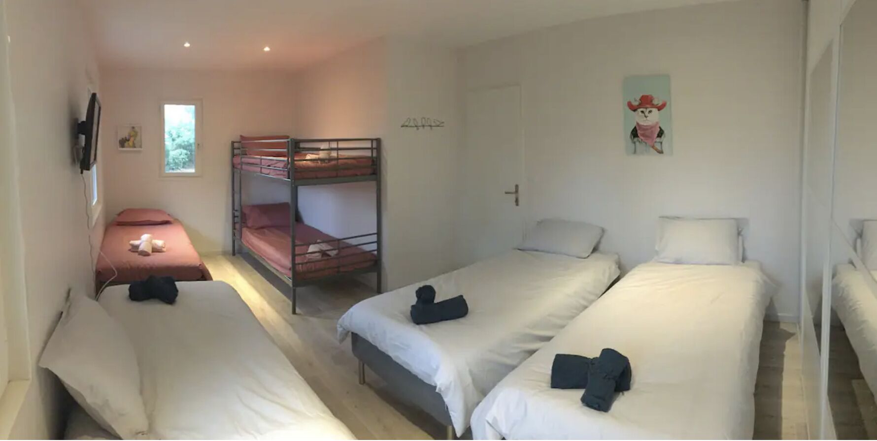 Un dormitorio con literas, una cama individual y un ventanal pequeño.