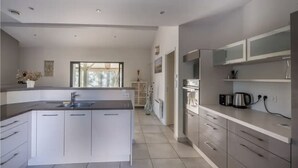 A modern kitchen with a large island, stainless steel appliances, and a view of the outdoors.