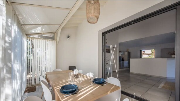 A dining area with a wooden table, white chairs, and a glass partition.
