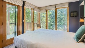 A bedroom with a large bed, wooden windows, and a view of trees. - High Altitude Haven 3 Bedroom Home by RedAwning (Alma)