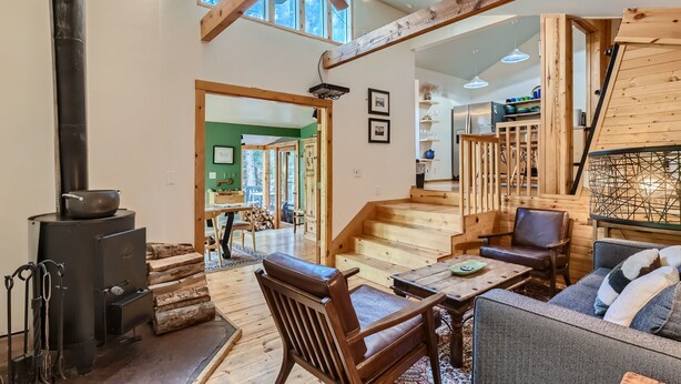A spacious living area with a fireplace, wooden furniture, and a staircase leading to another level. - High Altitude Haven 3 Bedroom Home by RedAwning (Alma)