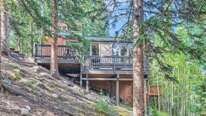 A multi-level cabin with a wooden deck and a balcony, surrounded by dense forest. - High Altitude Haven 3 Bedroom Home by RedAwning (Alma)