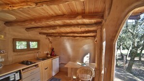 Un intérieur rustique en bois, avec un coin cuisine comprenant un évier, une cuisinière et des placards en bois.