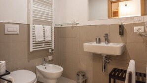 Uma casa de banho moderna com sanita, bidé, lavatório e barra de toalhas.