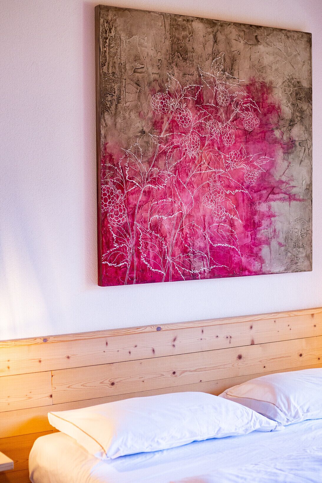 A room with a wooden headboard, a bed with white bedding, and a large abstract painting on the wall.