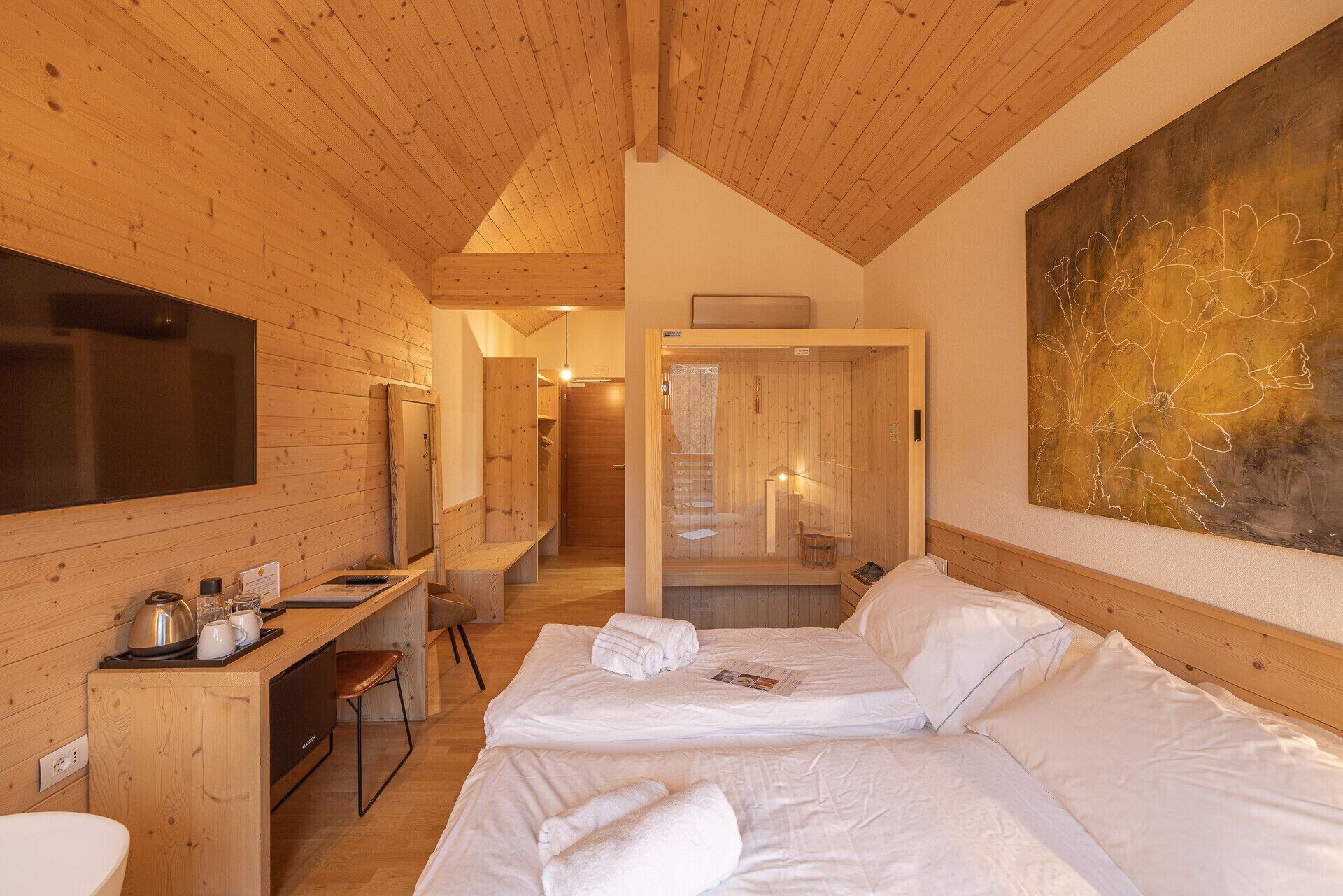 Una stanza in baita di legno con un letto, una scrivania e un grande quadro.