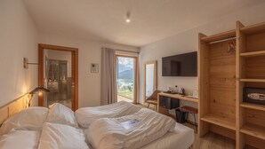 Ett sovrum med en säng, ett skrivbord, en tv och utsikt över bergen.