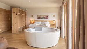 Une salle de bain moderne avec une baignoire sur pieds, des étagères en bois et une grande fenêtre avec des rideaux.