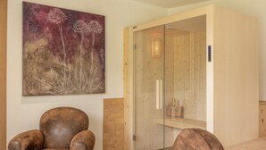 Un salon moderne avec un canapé en cuir marron, une petite table basse ronde et un grand tableau abstrait accroché au mur.