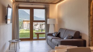 Ein gemütliches Zimmer mit Holzboden, einer Couch mit Kissen, einem Tisch und einer Lampe.