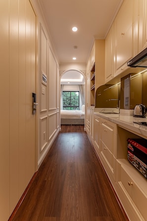 A narrow hallway with wooden flooring, white cabinetry, and a bed at the end. - Golden Sun Apartment & Hotel (Ho Chi Minh City)