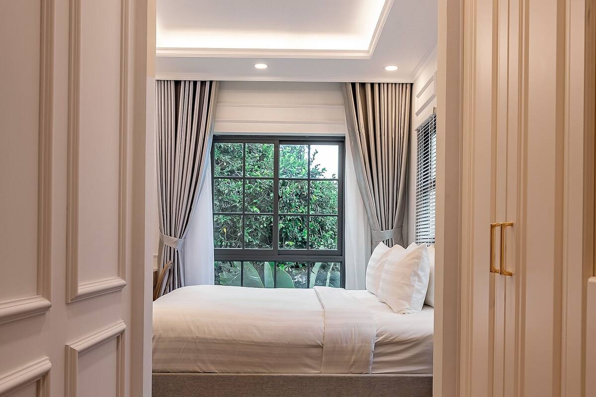 Ein Schlafzimmer mit großem Fenster, einem Bett und einem Kleiderschrank.