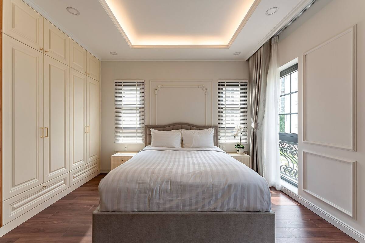 Ein Schlafzimmer mit einem großen Bett, eingebauten Schränken und einer Deckenleuchte.