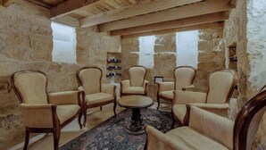Una stanza con pareti in pietra, travi in legno e sei poltrone imbottite disposte attorno a un tavolo centrale.