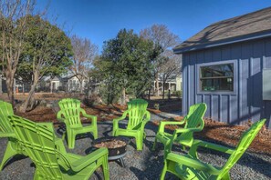 Outdoor seating with chairs and a fire pit, surrounded by trees and a building. - The Homestead Estate (Fredericksburg)