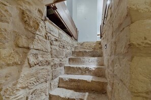 A narrow stone staircase leading upwards in a building with rough, textured walls. - The Homestead Estate (Fredericksburg)