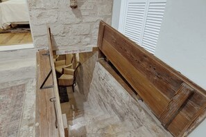 A narrow, rustic stairway with a wooden bench and a sign that reads "Mind Your Head."