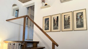 A wooden staircase with a handrail, a mirror, and four framed pictures on the wall. - Romantic Nest Florence Studio (Firenze)