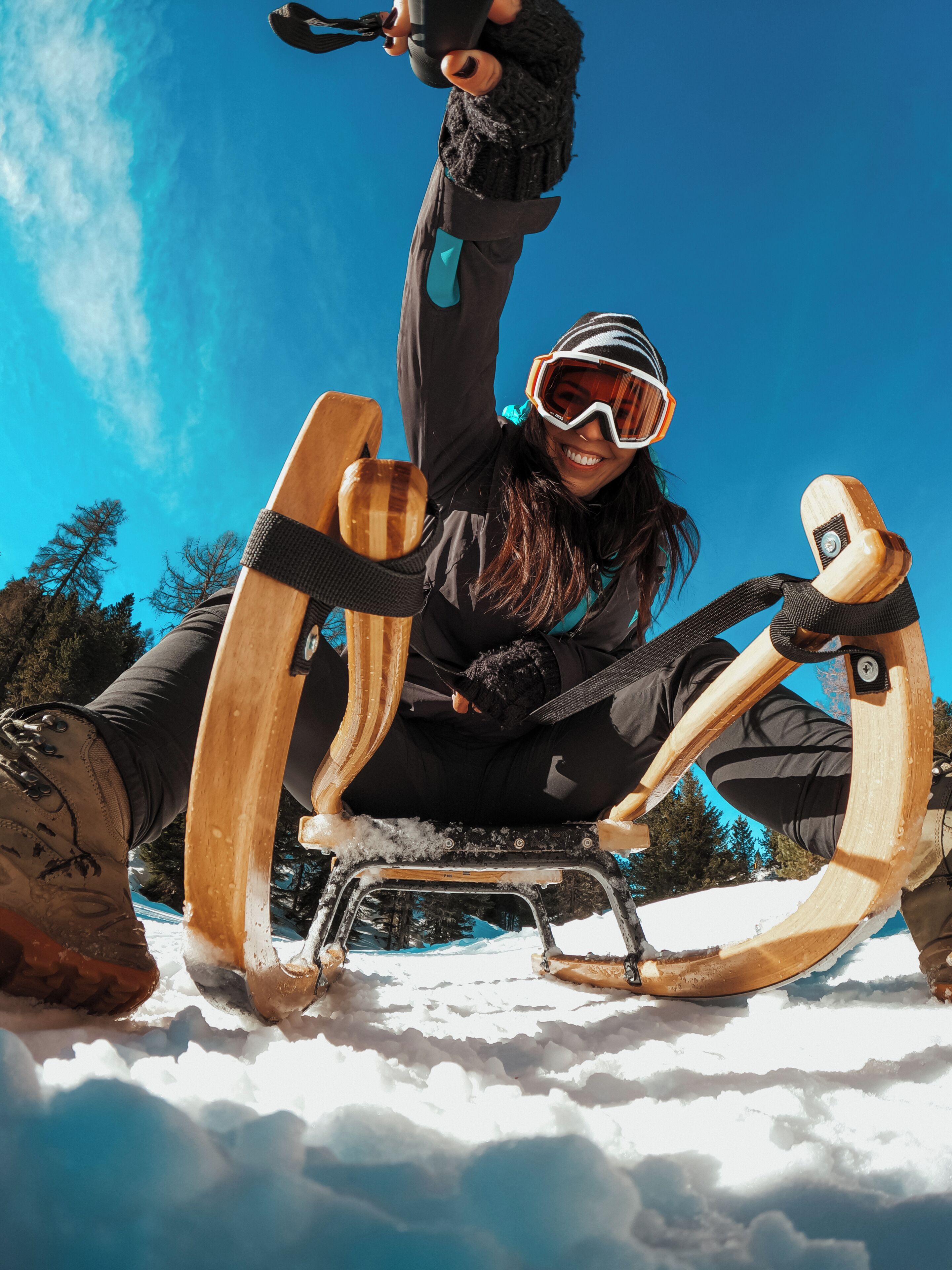 A person seated on a sled-like structure in a snowy outdoor setting.