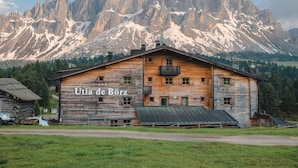 A rustic wooden building labeled "Utria de Börz" with a mountainous backdrop. - Ütia de Börz Mountain Lodge (San Martino in Badia)