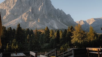 Eine Holzterrasse mit Bänken und Tischen mit Blick auf eine gebirgige Landschaft.