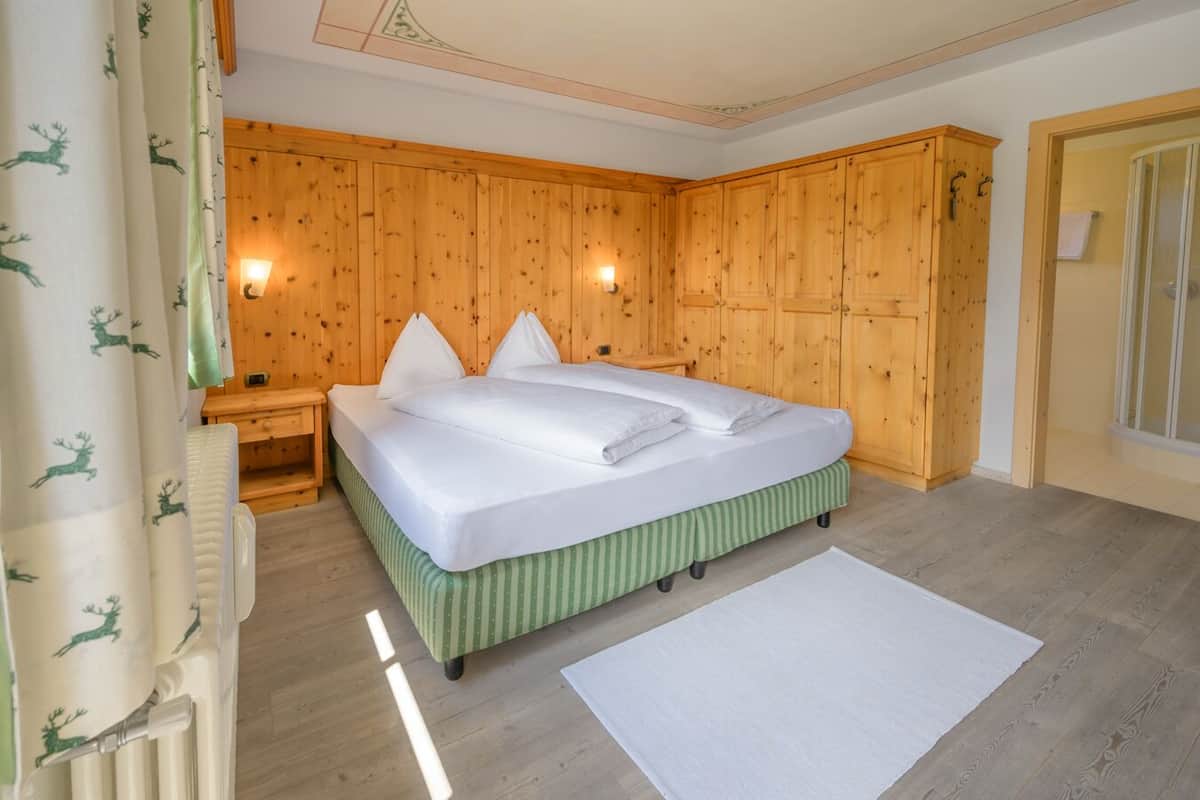 Une chambre à coucher avec une tête de lit en bois, un lit avec une literie blanche, une table de chevet et un pied de lit à rayures vertes.