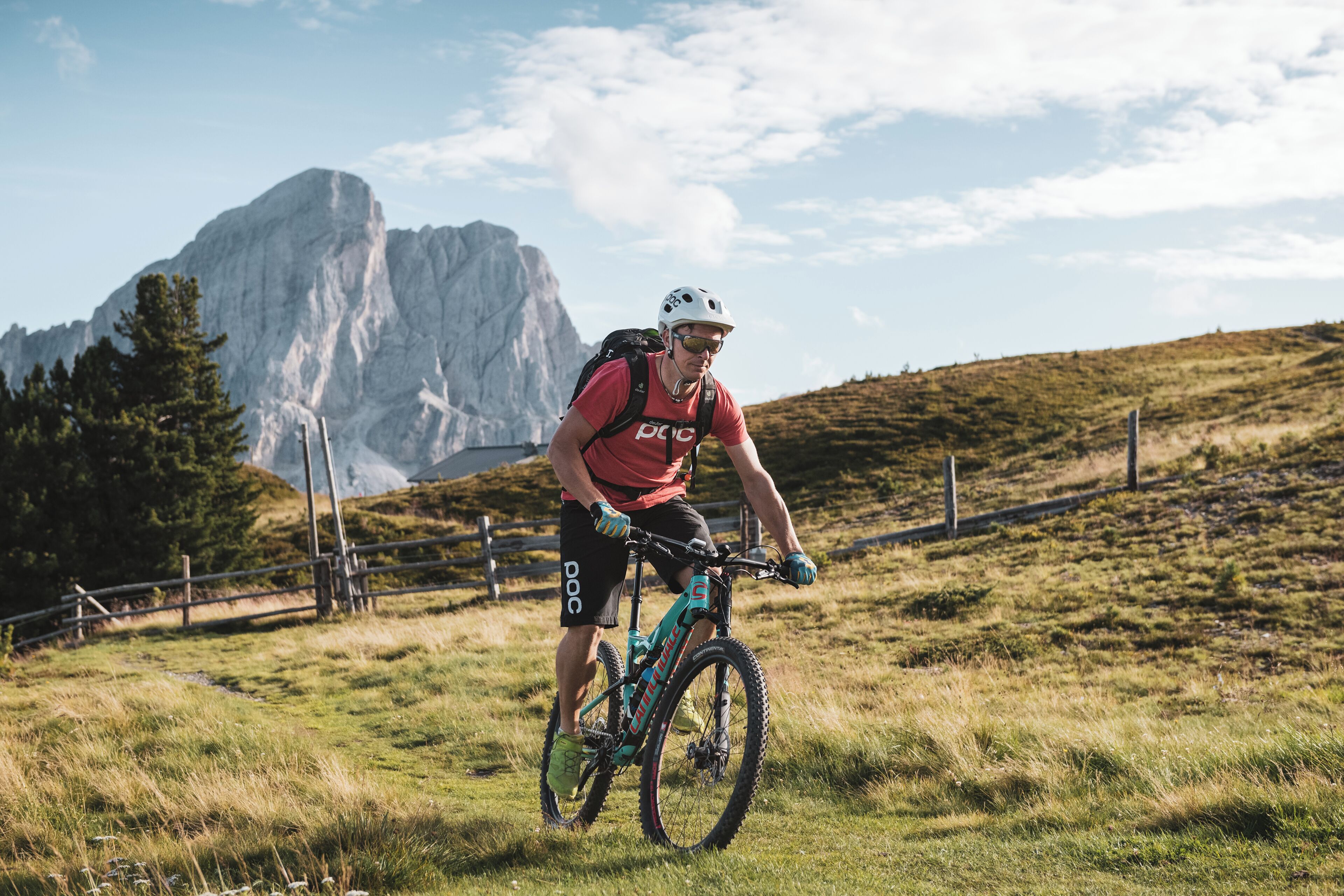 A mountain biker on a trail with a rocky mountain in the background.