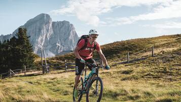 A mountain biker on a trail with a rocky mountain in the background.