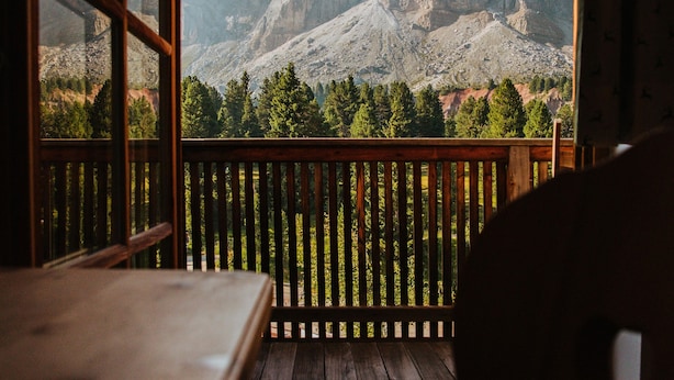 A wooden deck with a view of rugged mountains through a large window. - Ütia de Börz Mountain Lodge (San Martino in Badia)