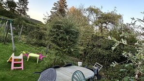 A round table with chairs in a grassy outdoor area, surrounded by greenery and trees. - Gîte Chez Mimi à Anor (Anor)
