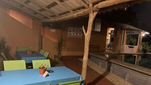 An outdoor dining area with tables and chairs, a wooden pergola, and a sign indicating a no-smoking policy. - Casa Calamar Zihuatanejo (Gro)