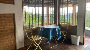 A room with a table covered by a blue tablecloth, a chair, and a window with metal bars. - Casa Calamar Zihuatanejo (Gro)