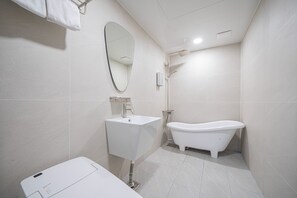 Un baño moderno con un lavabo blanco, una bañera independiente y un espejo grande.