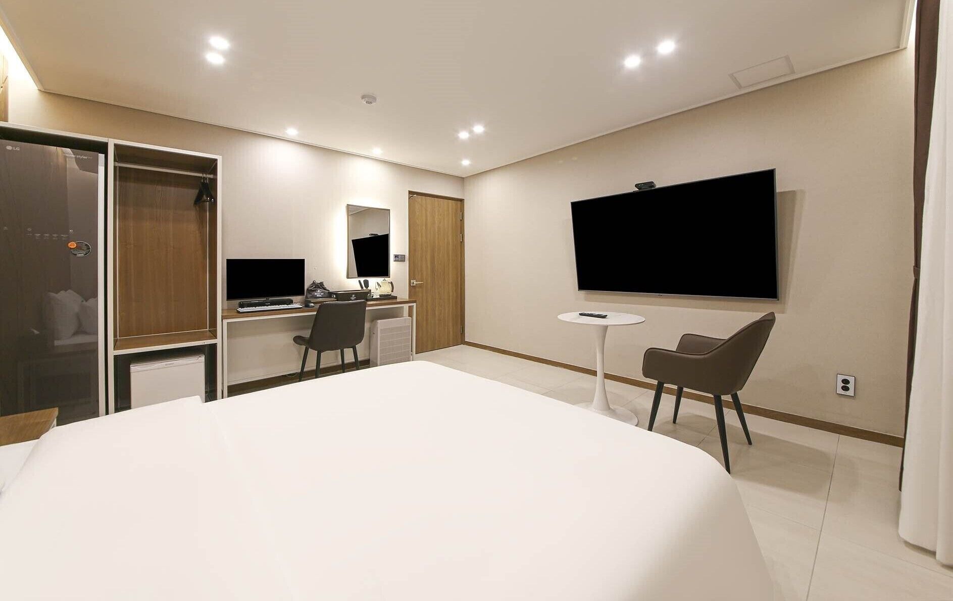 Een moderne hotelkamer met een groot bed, een bureau met een computer, een televisie en een klein tafeltje.