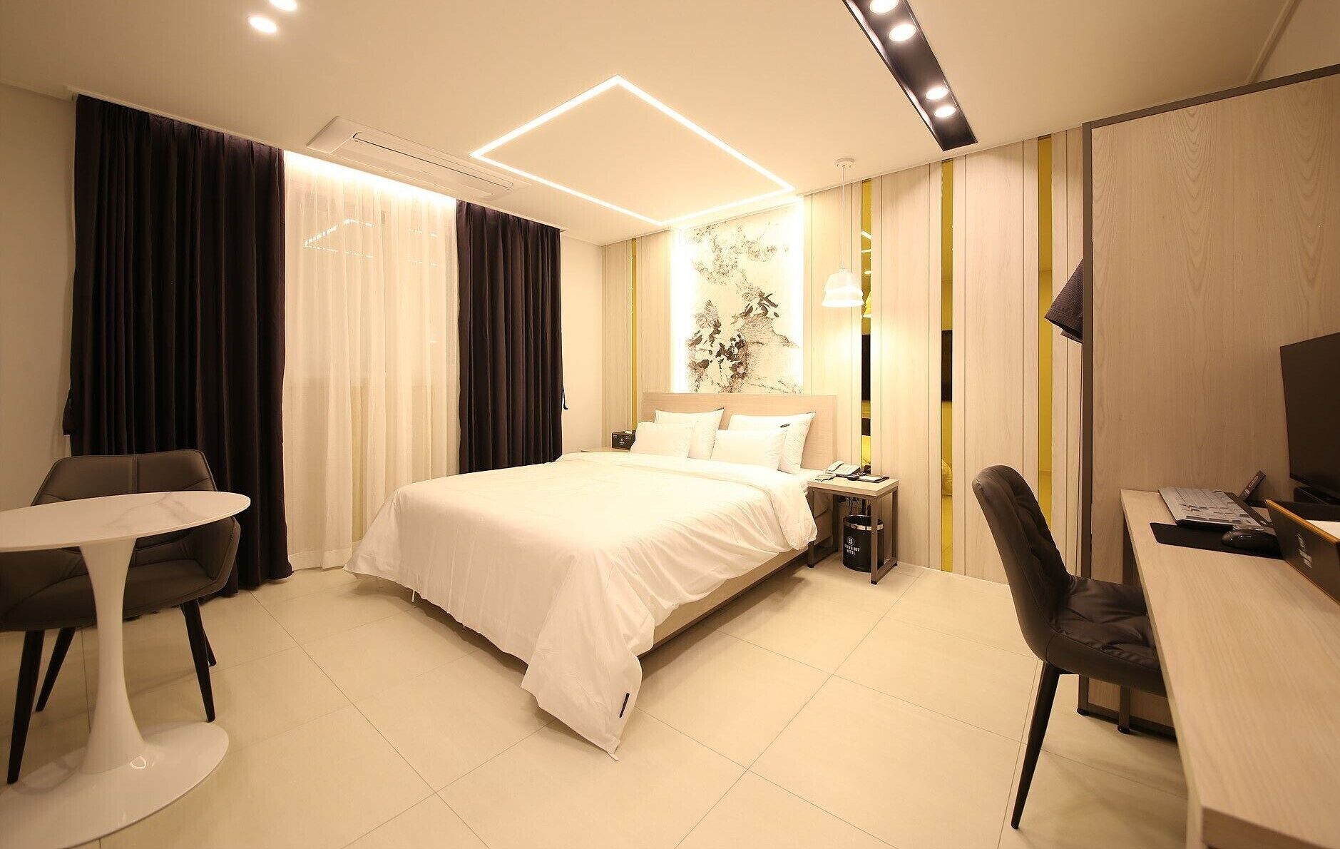 Une chambre d’hôtel moderne avec un grand lit, un bureau, une chaise et une petite table.