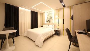 Une chambre d’hôtel moderne avec un grand lit, un bureau, une chaise et une petite table.