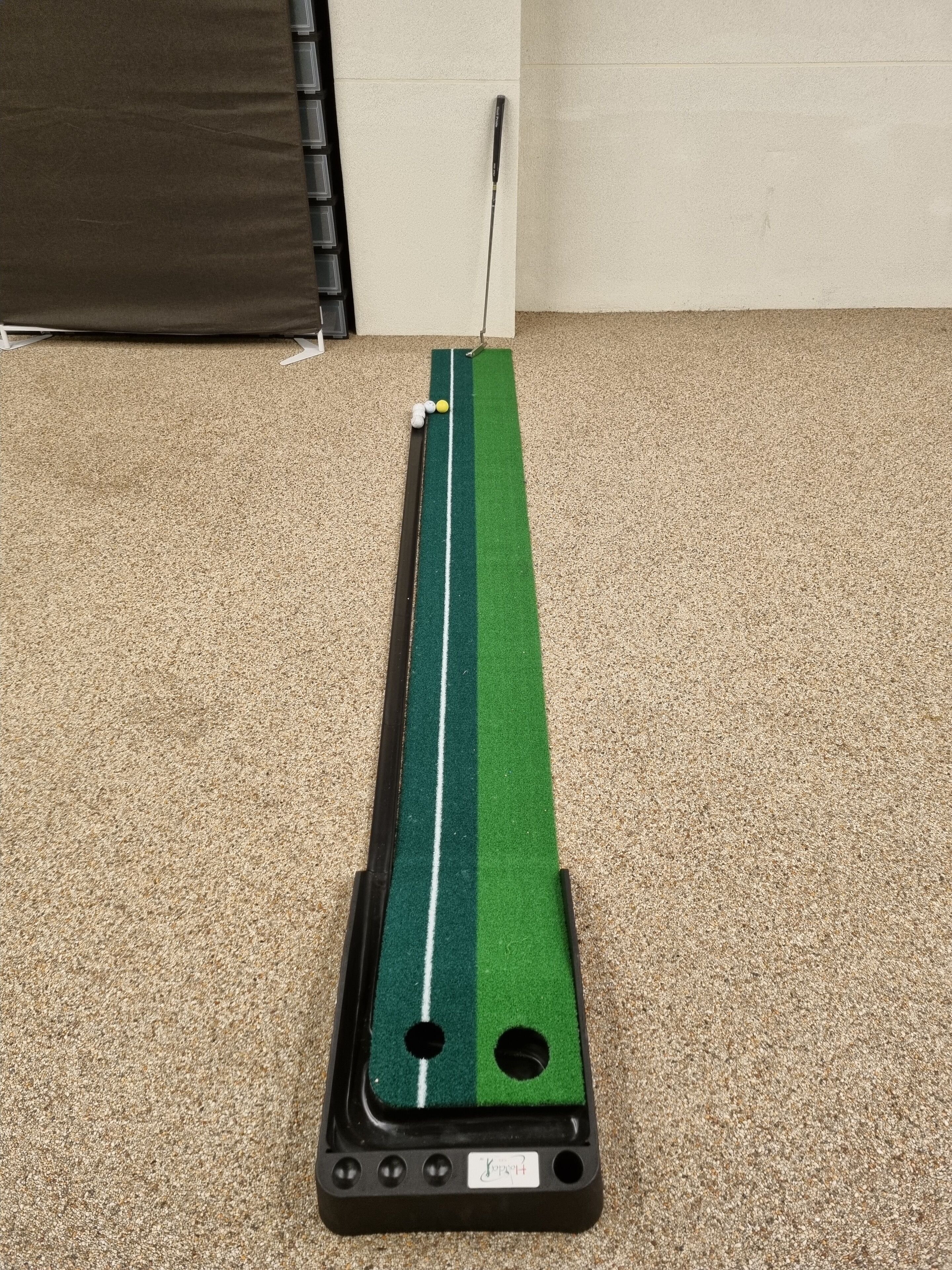 A putting green with a golf club and balls.