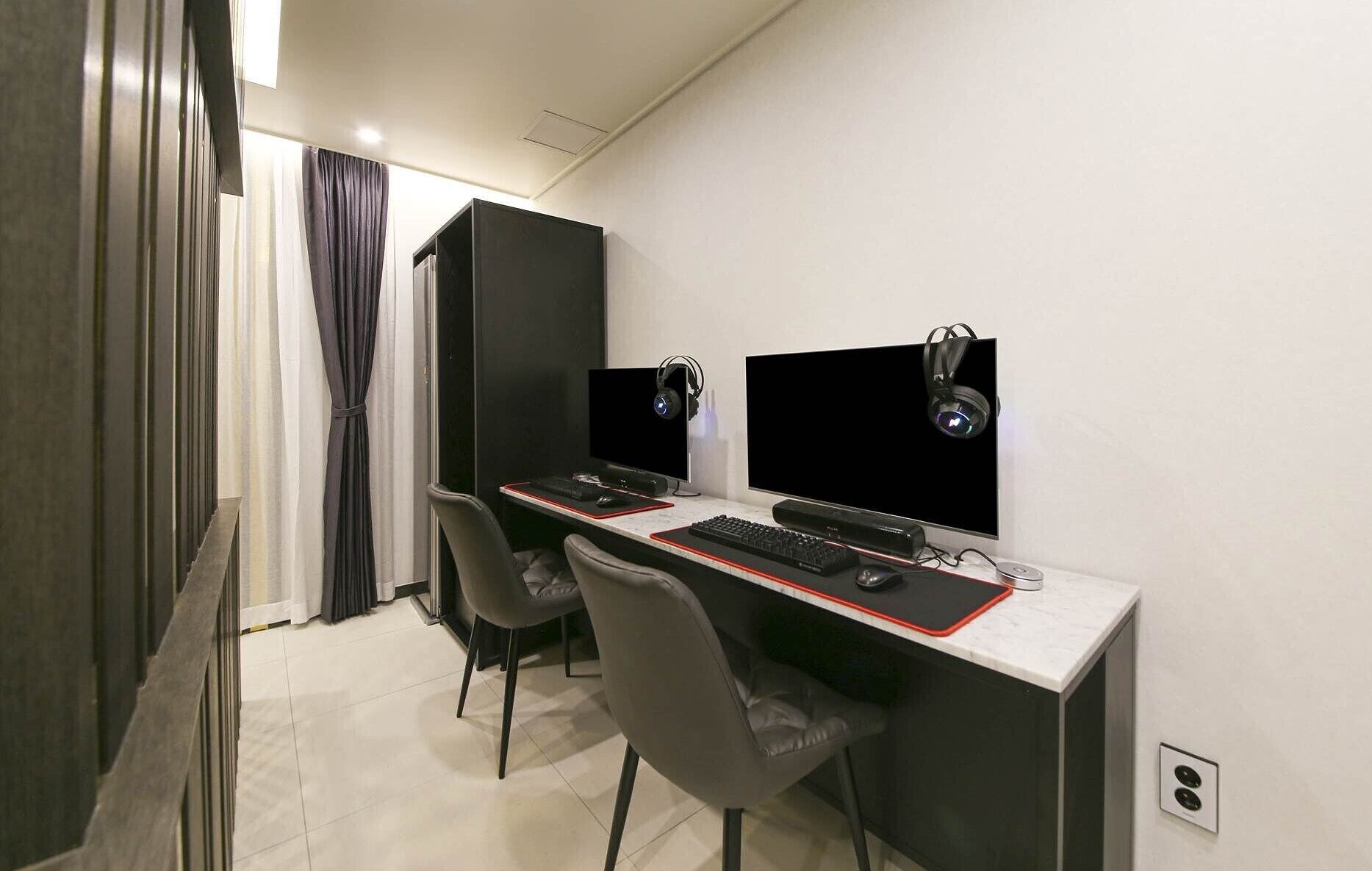 Um espaço de escritório moderno com duas mesas, cada uma com monitor de computador, teclado e fones de ouvido.